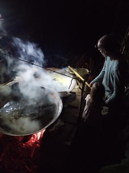 Michael tends to the boiling cane juice , which is bubbling away in two pilas - traditional copper pots special for this process.
