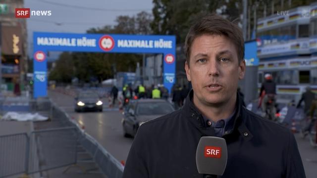 Standbild aus der Live-Sendung «Schweiz Aktuell» vom 27.09.2024: Hinter dem Reporter ist der Fahrradkorso zum Gedenken an Murel Furrer zu sehen, sowie der Zielbereich des Radrennens.