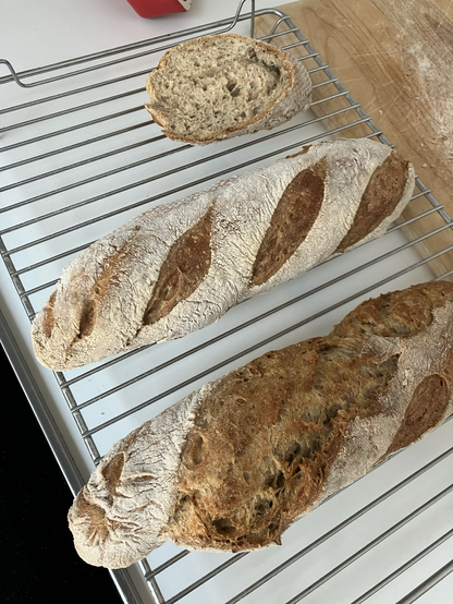 2 baguettes on a rack plus the remains of a third one showing the soft crumb.