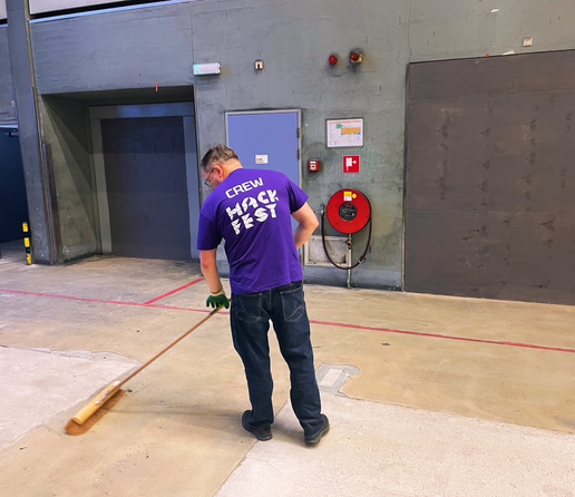 Person from the back sweeping the floor wearing a hackfest crew shirt
