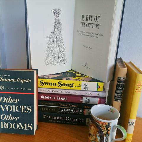 A stack of books by and on Capote, in front of which stands a coffee cup