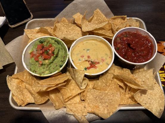 A photo I took of the chips and trio dip from Buffalo Wild Wings. You can see salsa, cheese dip and guacamole along with tortilla chips.