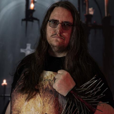 Max mit Anaphylaxie-Shirt vor brennenden Kerzen. Die Hand ist zur Faust geballt und am Arm trägt er ein Nietenarmband.