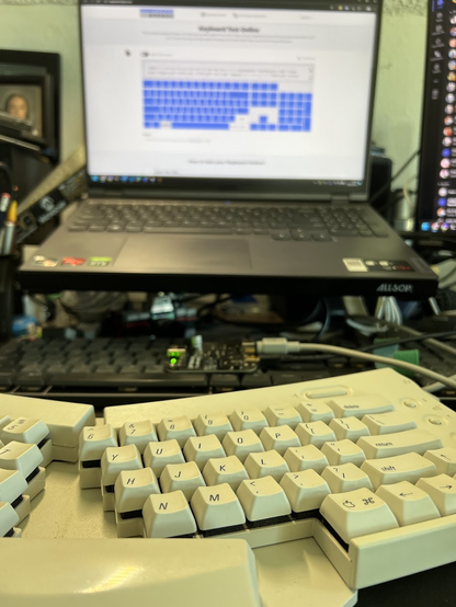 Desk photo of the Apple Adjustable Keyboard connected to an ADB-USB Wombat and then to a laptop, showing a keyboard tester page with all keys marked as working except for right modifiers, which work but aren't differentiated.