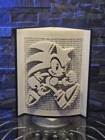 A photo showing a book sculpture featuring a three-dimensional rendition of Sonic the Hedgehog along the edges of its pages.