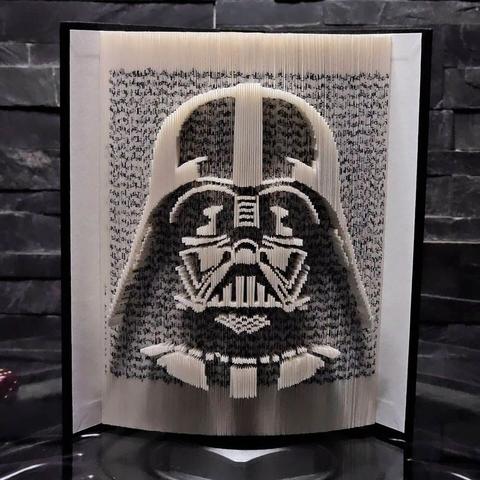 A photo showing a book sculpture featuring a three-dimensional portrait of Darth Vader along the edges of its pages.