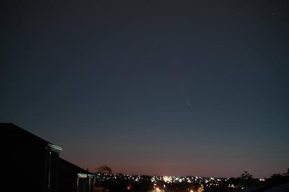 Looking to the Eastern horizon over Perth suburbs, a two story house to the left, silhouetted against the gradually reddening sky.
Comet Tsuchinshan-ATLAS is rising above the lights of the suburbs.