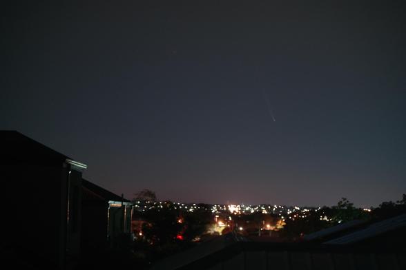 Looking to the Eastern horizon over Perth suburbs, a two story house to the left, silhouetted against the gradually reddening sky.
Comet Tsuchinshan-ATLAS is rising above the lights of the suburbs.