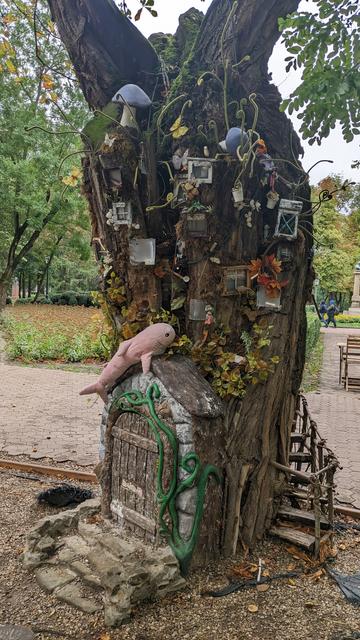 Rosåhaj on the roof of a mini house built next to a decorated tree stump.