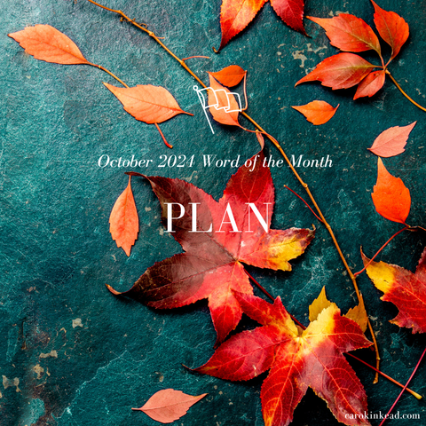 Two large red-yellow autumn leaves, surrounded by smaller orange leaves, on a surface of blue slate. Over this are the words "October 2024 Word of the Month: Plan”