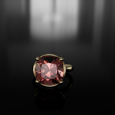 Dark pink faceted stone is set into a yellow gold ring, you can only see the claws and a small amount of the bezel around the ring. The background is dark, nearly black with some grey shadows out of focus