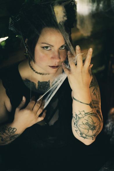 Witch in a dark hut playing with spider webs