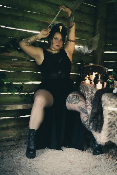 Witch sitting in a dark hut, playing with spider webs over her head