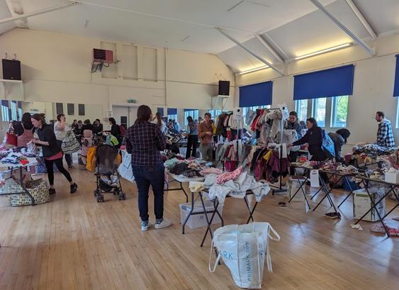 Tables and rails are decked out with children's clothes in a big hall for one of Sustainable Starts clothes swap events.