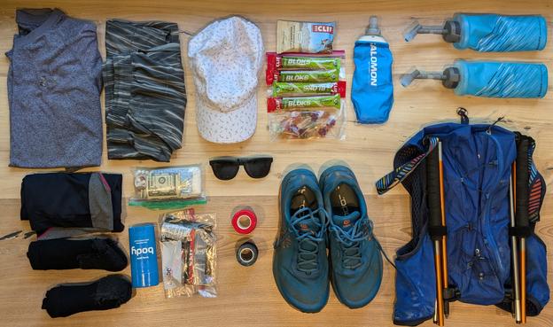 Load out of trail running kit for a 27 mile race including shoes, hat, shirt, shorts, nutrition, hydration containers, backpack, sunglasses and emergency toilet paper.