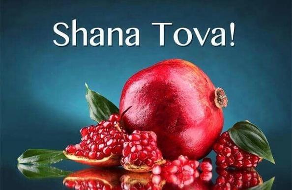 The words “Shana Tova!” above a pomegranate and some pomegranate seeds.