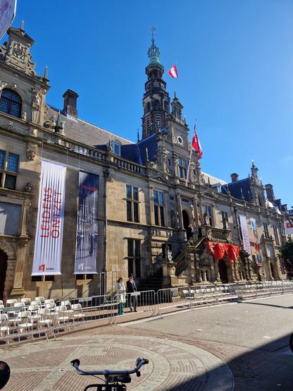 The frontage of Leiden city hall decorated with banners and the city flag. On the pavement a lot of chairs are standing ready for the viewers of the great parade that will be held this afternoon.