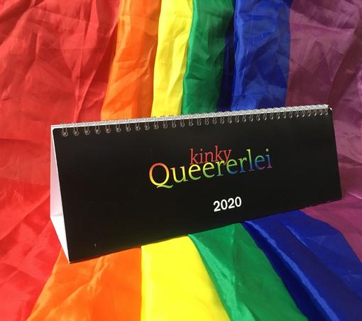 Ein Aufsteller im Querformat mit Ringbindung. Der Titel ist „kinky Queererlei 2020“. Der Aufsteller steht auf einer teilweise zerknüllten Regenbogenflagge.