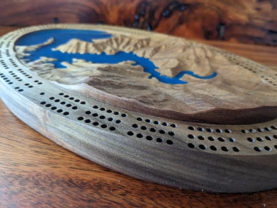 This is a cribbage board carved from Poplar featuring a scene from Western North Carolina.