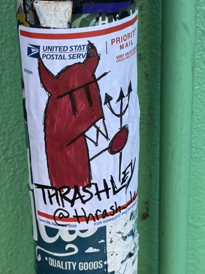 A little demon drawn in red ink with black outlines on a USPS mailing label and stuck on a pole. The demon is cartoony and holding a little trident. Below the demon is text that says "Thrashley @thrash_lee".