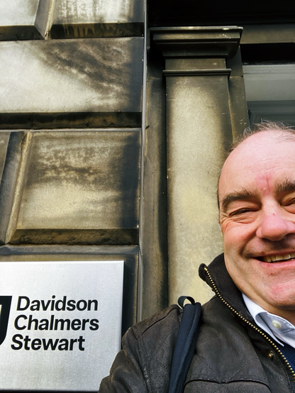 Old man smiling outside stone office