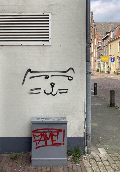a city wall containing a spray painted smiling cat