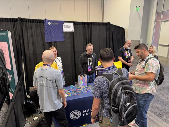 Board members discussing things with people around the booth