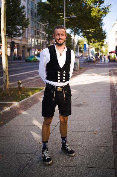 Portrait eines jungen Manns in Zimmermannskluft auf der Straße.