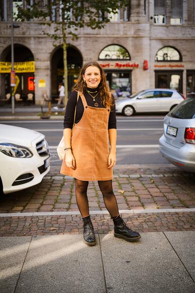 Portrait einer jungen Frau in Kordkleid auf der Straße.