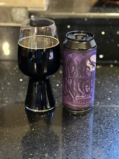 A stout glass of inky black beer, next to a dark purple and black can. “Night Witch” is scrawled on the side and a single wing plane flies across a pink moon