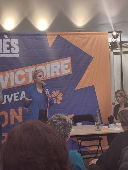 une salle, plafond blanc, des participants de dis, un homme prend la parole (Alexis Corbières)