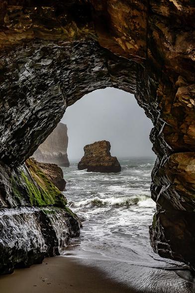 Troubled Waters

This is an image captured down in Shark Fin Cove on the central coast of California.
Captured from Shark Fin Beach this image looks out at the Pacific Ocean through a natural arch worn through a cliff that wraps around in front of the beach. 
There is a sea stack that sits near the center of the arch that is roughly 100 yards off shore and the waves run out in the middle of the arch. 
The fog is thick in this image and the vast Pacific Ocean blends into the fog in the background.