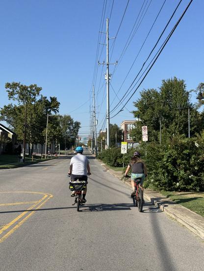 Two people on bikes riding on a city street