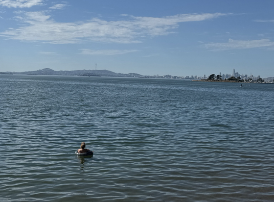 Woman floating in an inflatable in the bay, with San Francisco in the background