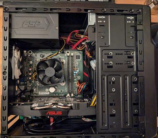 A picture of the insides of the same computer.

It houses a basic FSP 500W power supply in the top, two chassis fans (one on the rear acting as an exhaust, one in the front hidden by drive mounting brackets as an intake), the HP 280 G1 ATX motherboard with a stock HP LGA115x cooler over the Xeon CPU and an ASUS-branded RX570.

The wires inside are managed to the best of my abilities but still look somewhat messy, though not in the way of any airflow or fan blades at least.