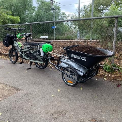An e-bike towing a converted wheelbarrow trailer