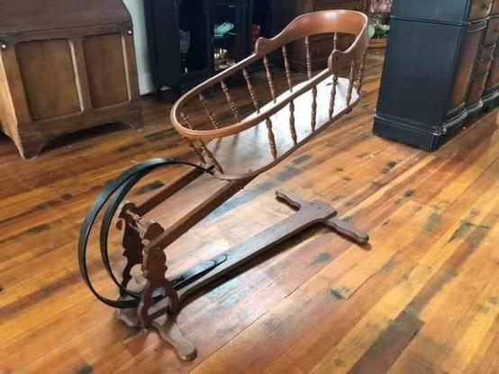 A wooden baby bed with a large hinge and metal coils on one side. The contraption allows the baby to be rocked to sleep/silence without needing move it by hand continuously.

It looks like a baby catapult.