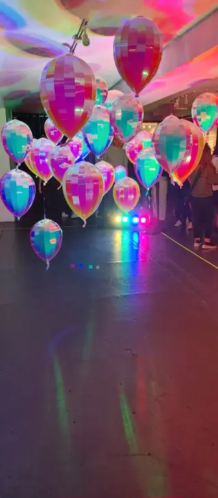 A picture of some colourful shiny balloons floating upwards in a room.