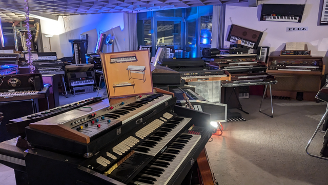 the inside of the eboardmuseum in Klagenfurt. On this photo of the second level of a large hall a lot of different keyboards can be seen. One very prominent one in the front.