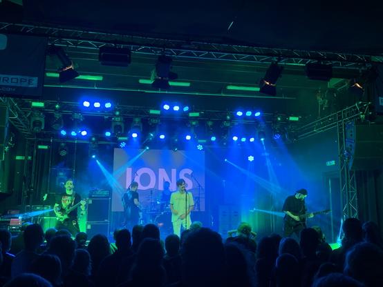 Ions on stage. Lighting is a mix of blue and green.