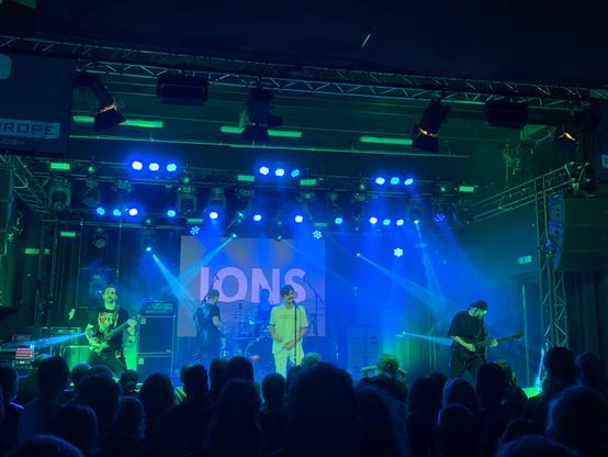 Ions on stage. Lighting is a mix of blue and green.