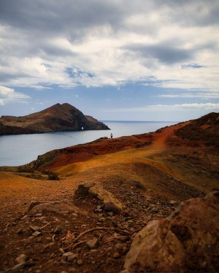 Coastal landscape with a indentation of the sea. In the middle is a woman who visually connects the landscapes