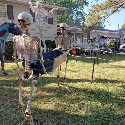 Two skeletons carrying an open coffin with another waving in the back.