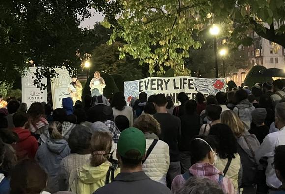 view of speakers over audience, with half of large white sign with black letters visible: "Every Life a Universe"