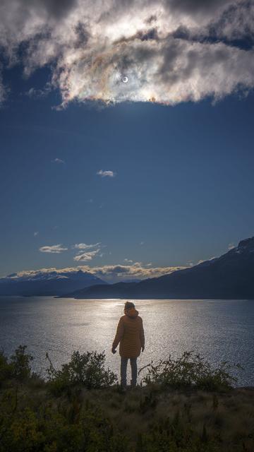 Annular eclipse photographed above lake and mountainous landscape.