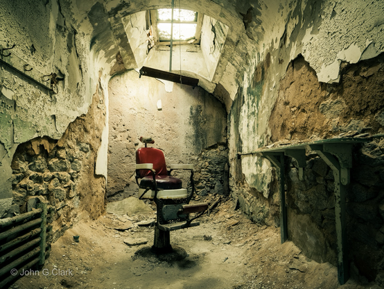 Red barber chair sits amidst rubble and decay from a crumbling room