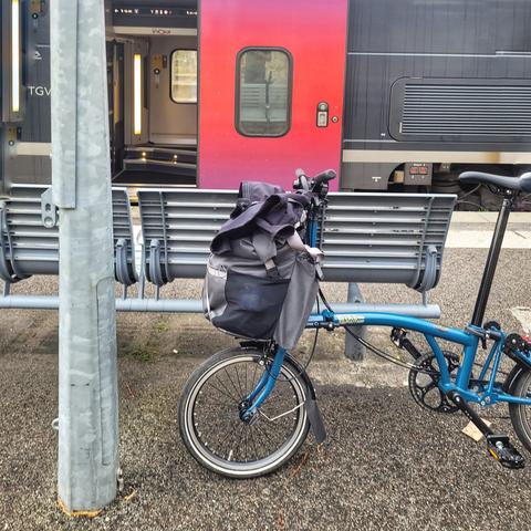 Un vélo pliant équipé d'un sac à l'avant, devant la porte d'un TGV, prêt à embarquer