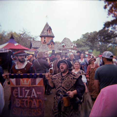 Costumed players walking and singing through a crowd at the 2023 Minnesota Renaissance Festival.