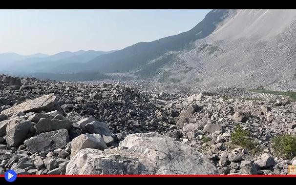 Valle priva di vegetazione ricoperta di pietre grigie ineguali, all'ombra di un pendio incombente. Nessuna abitazione o segno di attività umana  è visibile nella desolazione generale.