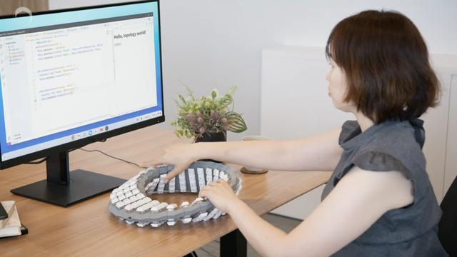 Photo of someone using a keyboard shaped like a Möbius strip
